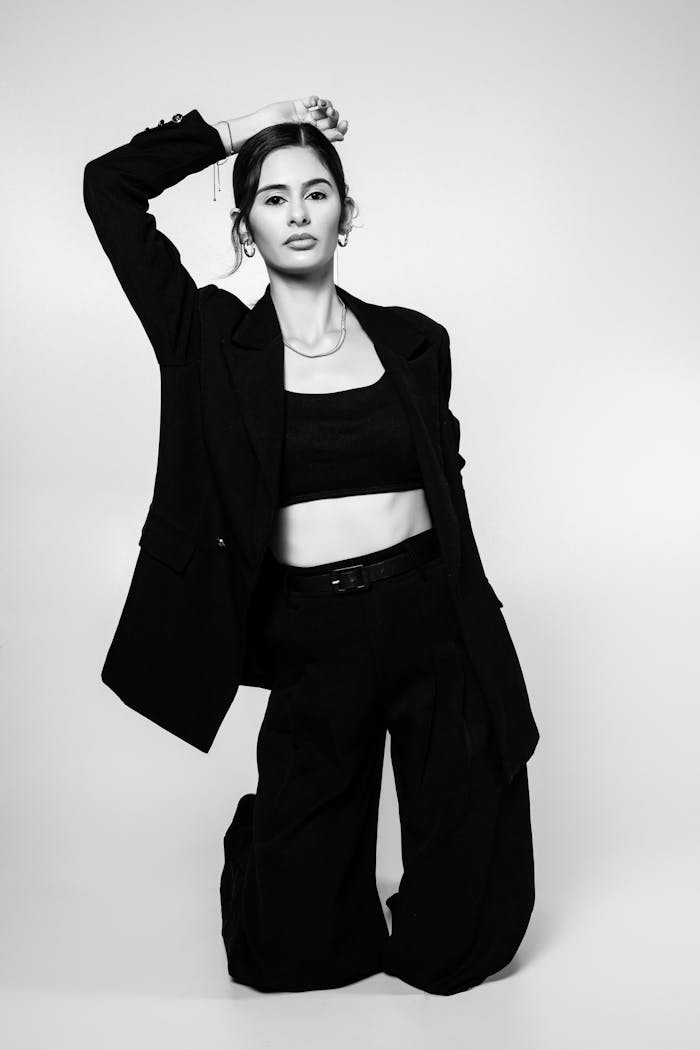 About Sophisticated black and white portrait of a woman in stylish attire kneeling, exuding modern elegance.